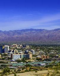 Landscape view of Tuscon with mountains in the background and cacti in foreground with cityscape in the center